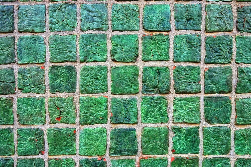 Grüne quadratische Mosaikfliesen mit hellgrauen Zementfugen in Nahaufnahme